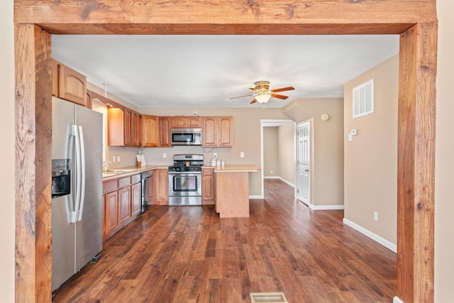 kitchen with appliances with stainless steel finishes, dark wood-type flooring, sink, and ceiling fan