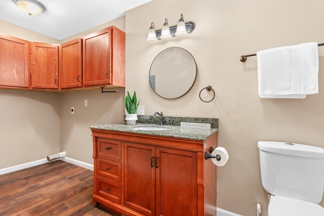 half bath with baseboards, toilet, wood finished floors, and vanity