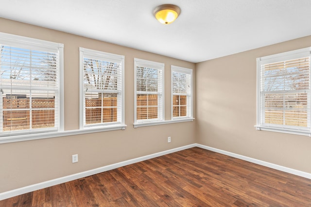 spare room featuring baseboards and dark wood-style flooring