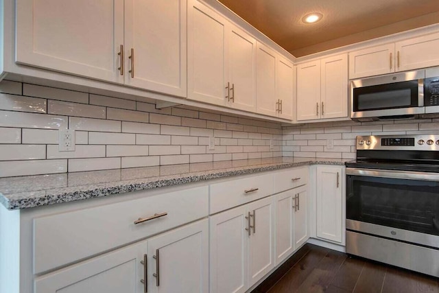 kitchen featuring appliances with stainless steel finishes, tasteful backsplash, white cabinetry, light stone countertops, and dark wood-type flooring