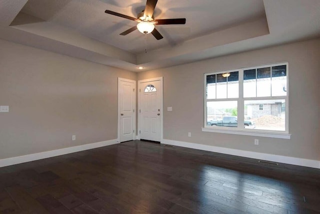 interior space featuring dark hardwood / wood-style floors, a raised ceiling, and ceiling fan