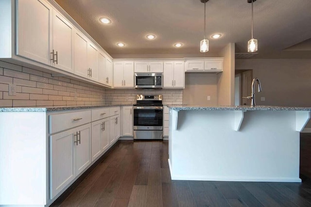 kitchen with sink, white cabinetry, stainless steel appliances, tasteful backsplash, and decorative light fixtures