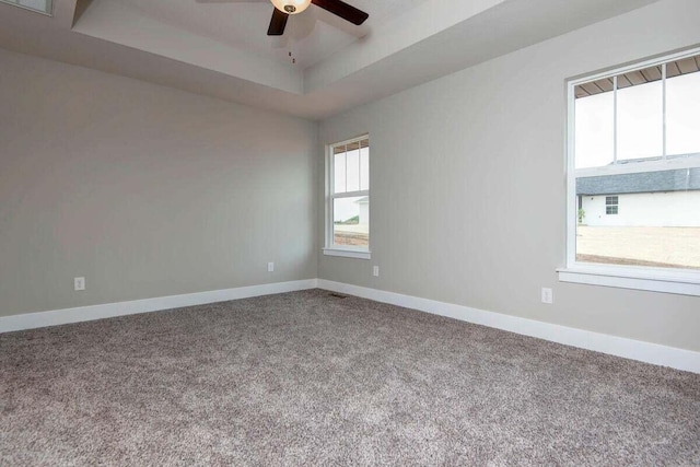 spare room with ceiling fan, a raised ceiling, and carpet floors