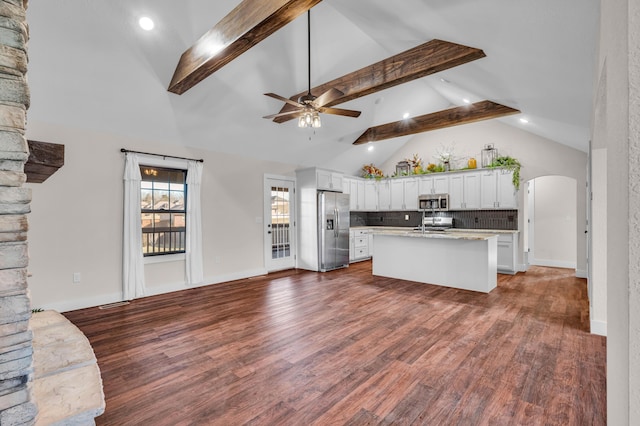 kitchen featuring ceiling fan, stainless steel appliances, tasteful backsplash, white cabinets, and a center island with sink