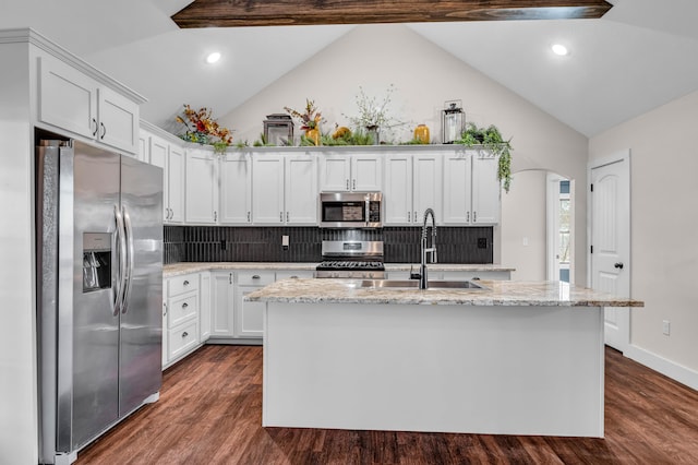 kitchen featuring lofted ceiling with beams, white cabinetry, stainless steel appliances, and an island with sink