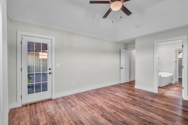 unfurnished bedroom featuring ensuite bathroom, access to outside, dark hardwood / wood-style flooring, ceiling fan, and multiple windows