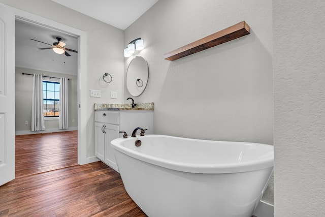 bathroom featuring ceiling fan, vanity, hardwood / wood-style floors, and a washtub