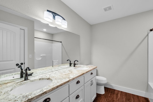 bathroom with hardwood / wood-style flooring, a shower, vanity, and toilet