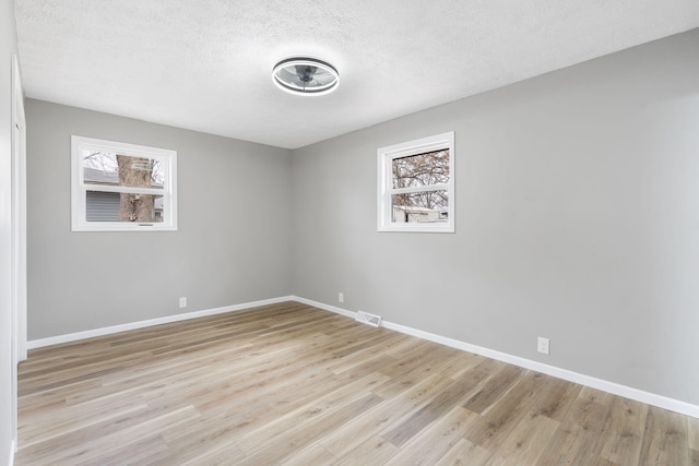 unfurnished room with a textured ceiling and light wood-type flooring