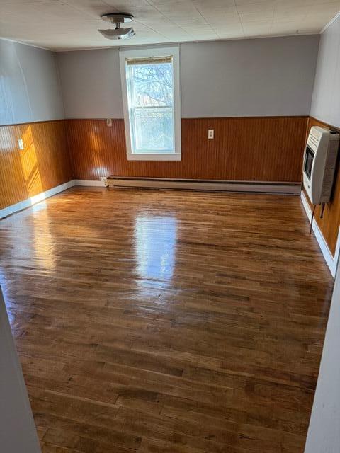 empty room with dark wood-type flooring and heating unit