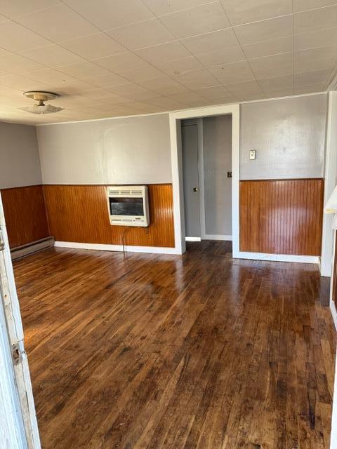 unfurnished room featuring heating unit, dark hardwood / wood-style flooring, and a baseboard radiator