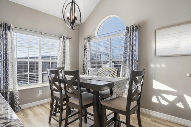 dining space featuring lofted ceiling, a wealth of natural light, a notable chandelier, and light hardwood / wood-style flooring