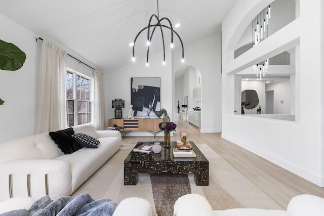 living room with high vaulted ceiling, light hardwood / wood-style floors, and a notable chandelier