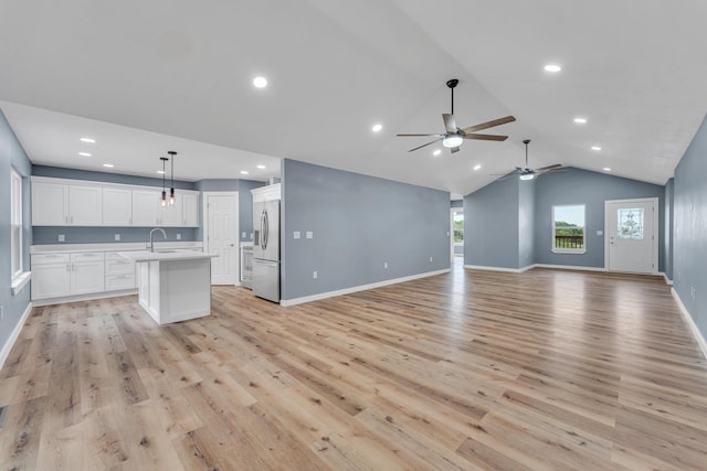 unfurnished living room with ceiling fan, lofted ceiling, sink, and light hardwood / wood-style flooring