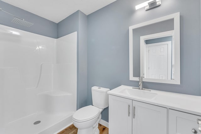 bathroom with a shower, hardwood / wood-style floors, vanity, and toilet