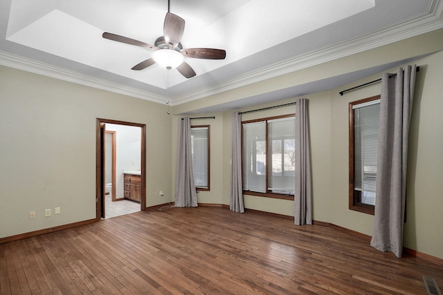 unfurnished bedroom with ensuite bathroom, dark wood-type flooring, ceiling fan, and a tray ceiling