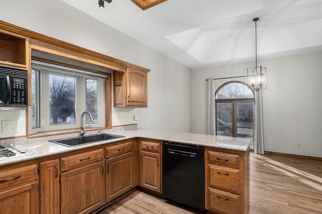 kitchen with sink, light wood-type flooring, kitchen peninsula, pendant lighting, and black appliances