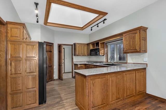 kitchen featuring dark wood-type flooring, sink, tasteful backsplash, appliances with stainless steel finishes, and kitchen peninsula