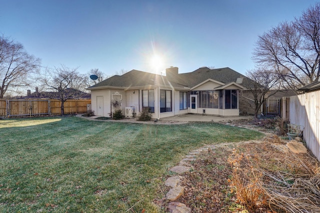 back of house featuring a sunroom, a patio, and a lawn