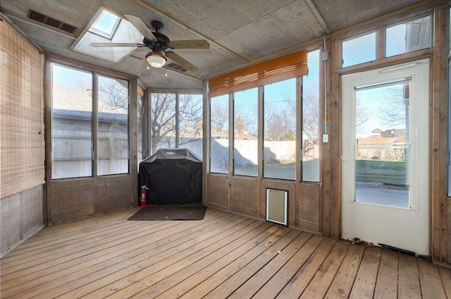 unfurnished sunroom with ceiling fan and a skylight