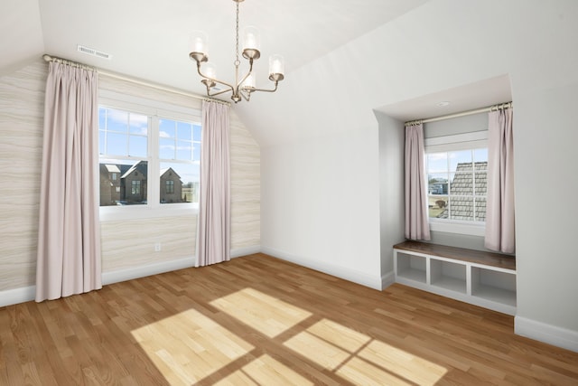 unfurnished dining area featuring lofted ceiling, hardwood / wood-style flooring, and an inviting chandelier