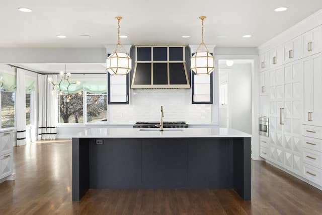 kitchen with white cabinetry, a center island with sink, and decorative light fixtures