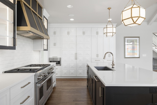 kitchen featuring pendant lighting, double oven range, sink, and an island with sink