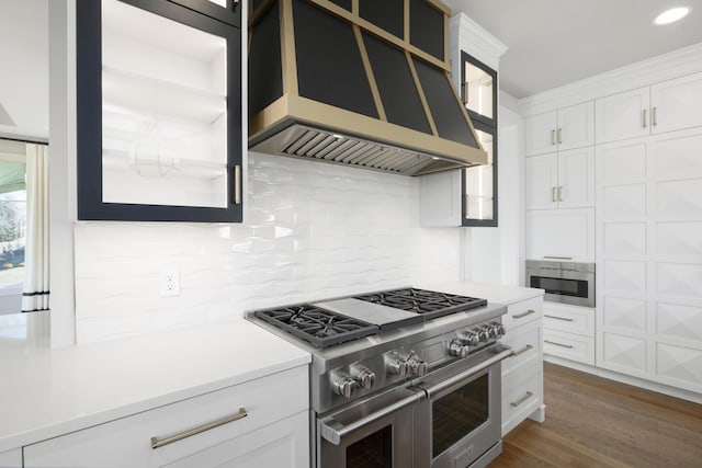 kitchen featuring white cabinetry, backsplash, dark hardwood / wood-style flooring, range with two ovens, and custom exhaust hood