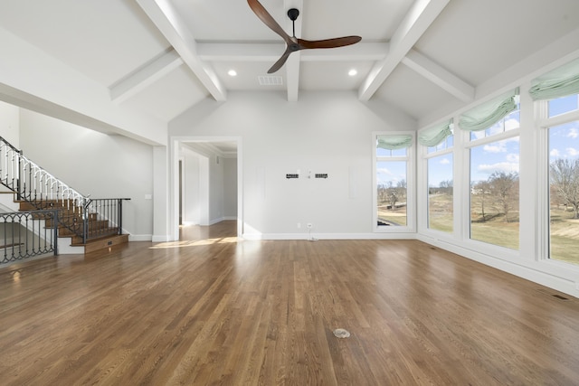 unfurnished living room with ceiling fan, wood-type flooring, lofted ceiling with beams, and a wealth of natural light