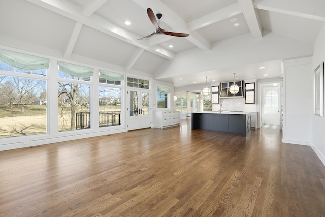 unfurnished living room with beamed ceiling, ceiling fan, dark hardwood / wood-style floors, and high vaulted ceiling