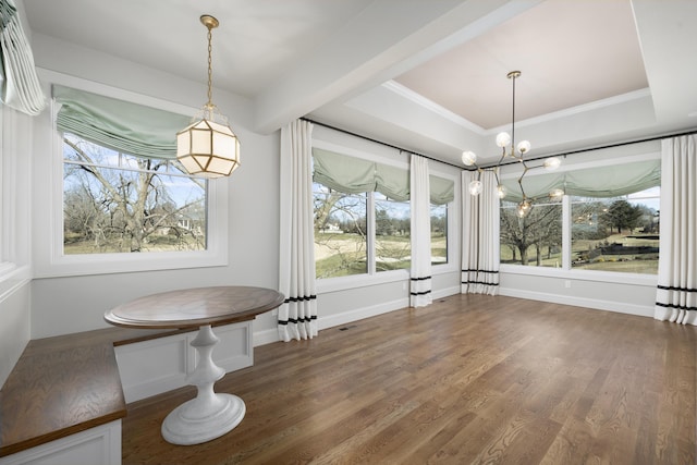 unfurnished dining area featuring dark hardwood / wood-style flooring, a tray ceiling, ornamental molding, and a chandelier