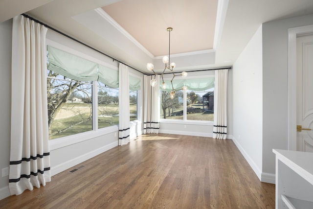 unfurnished dining area featuring a healthy amount of sunlight, a tray ceiling, and wood-type flooring