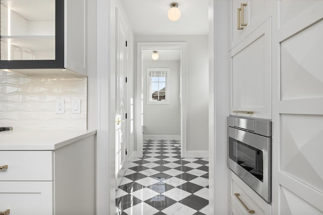 kitchen featuring stainless steel microwave, white cabinets, and decorative backsplash