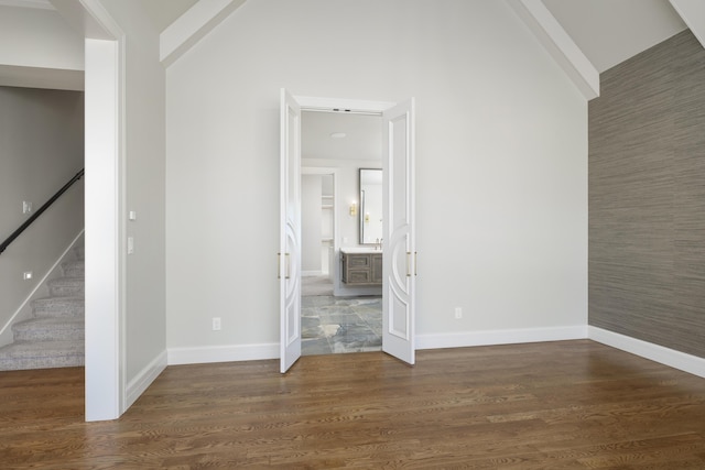 spare room featuring dark wood-type flooring, beam ceiling, and high vaulted ceiling