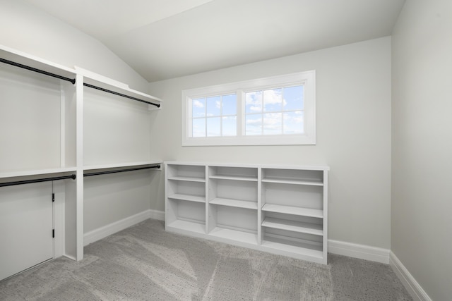 spacious closet with lofted ceiling and light colored carpet