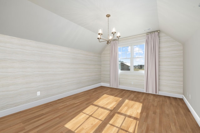 bonus room featuring vaulted ceiling, hardwood / wood-style floors, and a notable chandelier