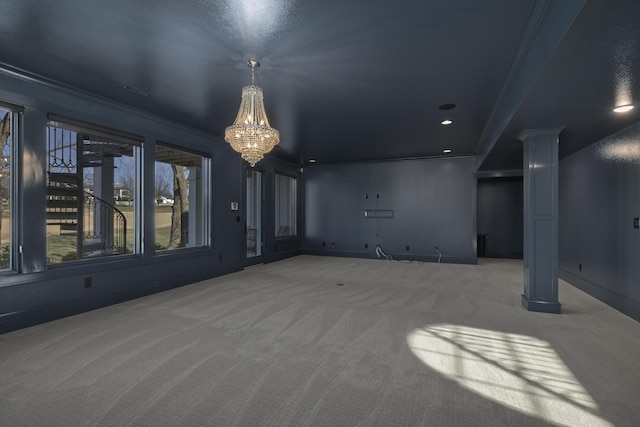 unfurnished living room with a notable chandelier, ornamental molding, decorative columns, and carpet