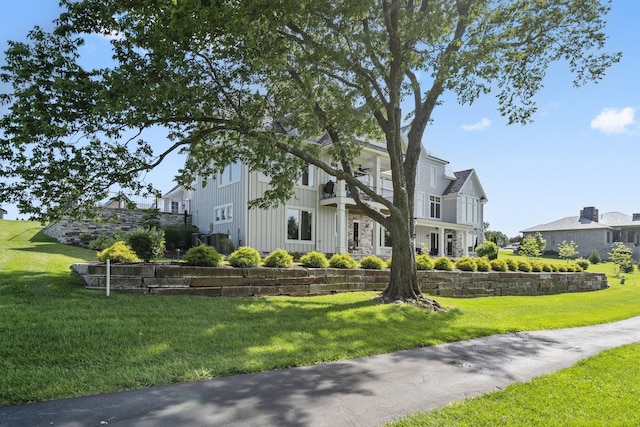 view of front of house featuring a balcony and a front lawn