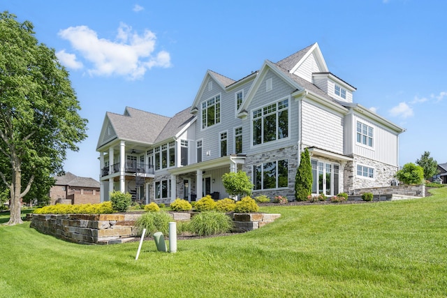 back of house featuring a balcony and a lawn