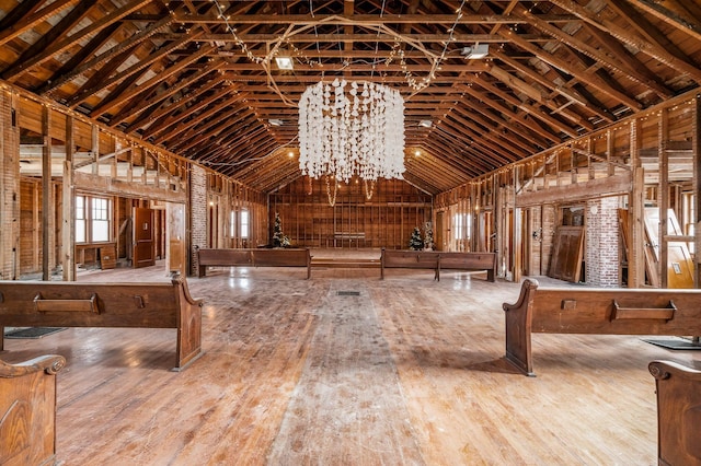 misc room with hardwood / wood-style flooring, an inviting chandelier, and high vaulted ceiling