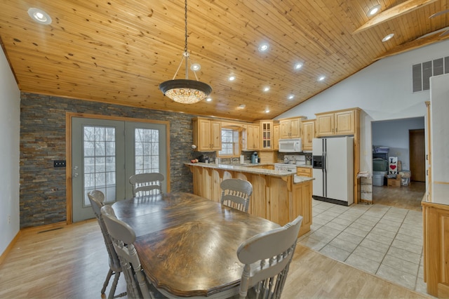 dining area with high vaulted ceiling, wood ceiling, and light hardwood / wood-style floors