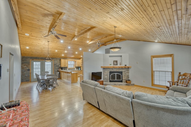 living room featuring a stone fireplace, light wood-type flooring, and wood ceiling