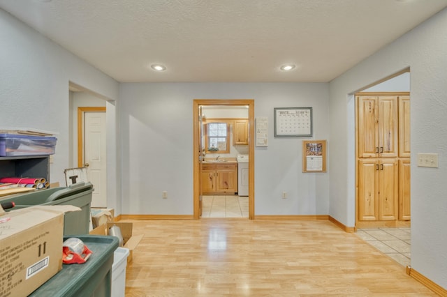 office space featuring sink, washer / dryer, light hardwood / wood-style floors, and a textured ceiling