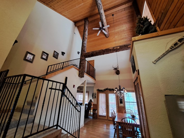 staircase with high vaulted ceiling, wooden ceiling, hardwood / wood-style floors, beamed ceiling, and ceiling fan with notable chandelier