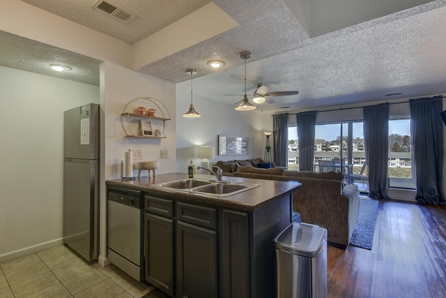 kitchen featuring sink, a textured ceiling, light tile patterned floors, appliances with stainless steel finishes, and ceiling fan