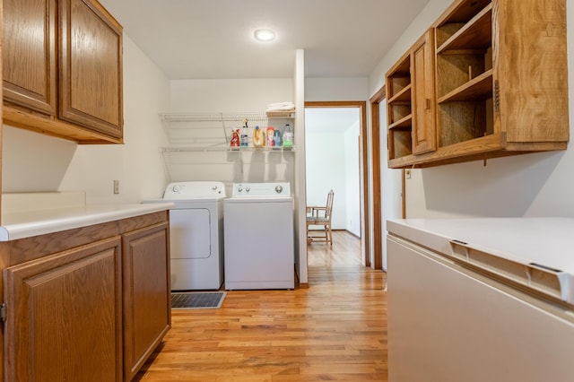 clothes washing area with separate washer and dryer and light hardwood / wood-style flooring