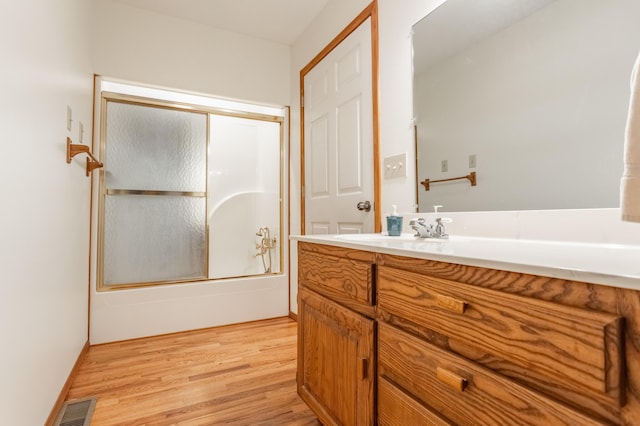 bathroom with vanity, hardwood / wood-style flooring, and bath / shower combo with glass door