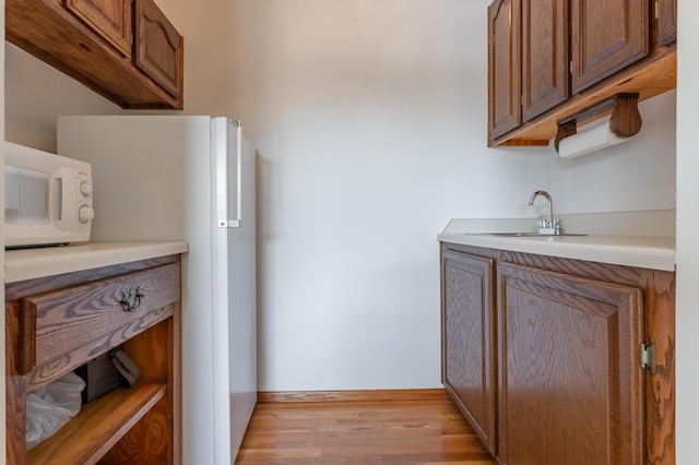 kitchen with sink, white appliances, and light wood-type flooring