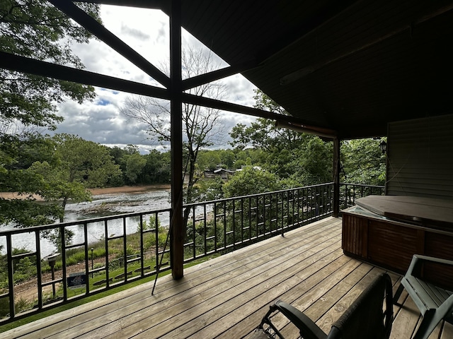 deck with a water view and a hot tub