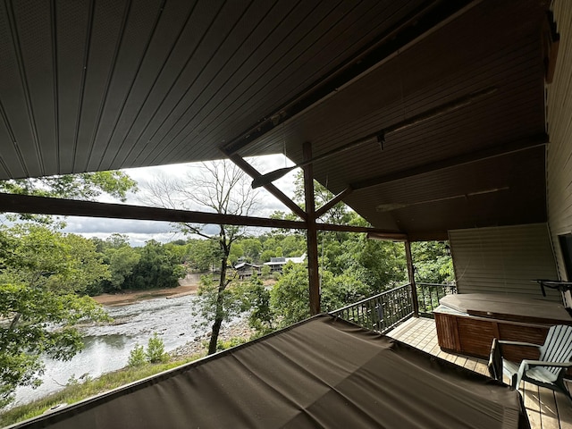 deck with a hot tub and a water view